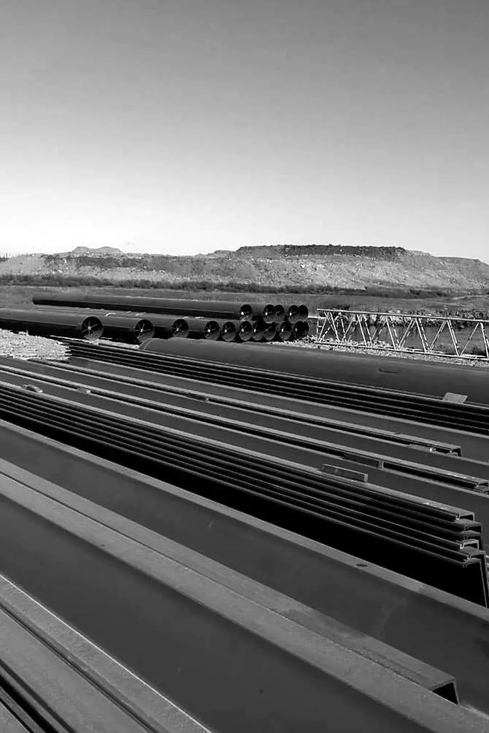 Large-diameter steel pipes and steel sections stacked in an open storage yard